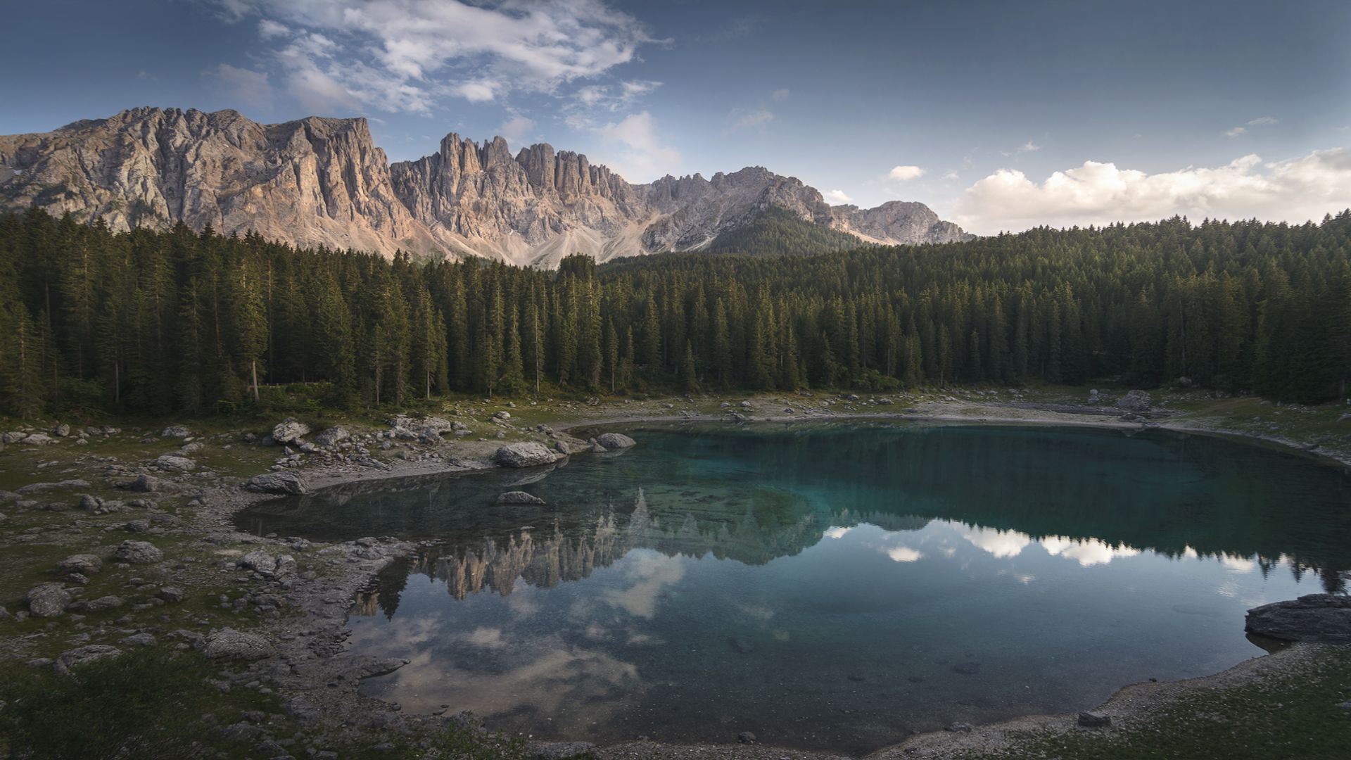 Paesaggio con montagne in lontananza e lago in primo piano circondato dalla foresta